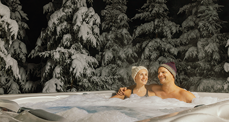 Couple with toques on sitting in hot tub in the winter
